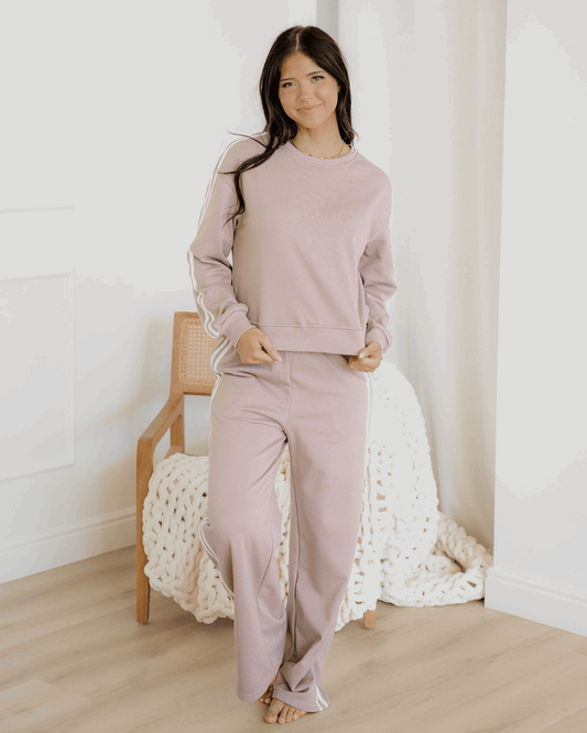 Woman wearing a light pink loungewear set in a cozy room.