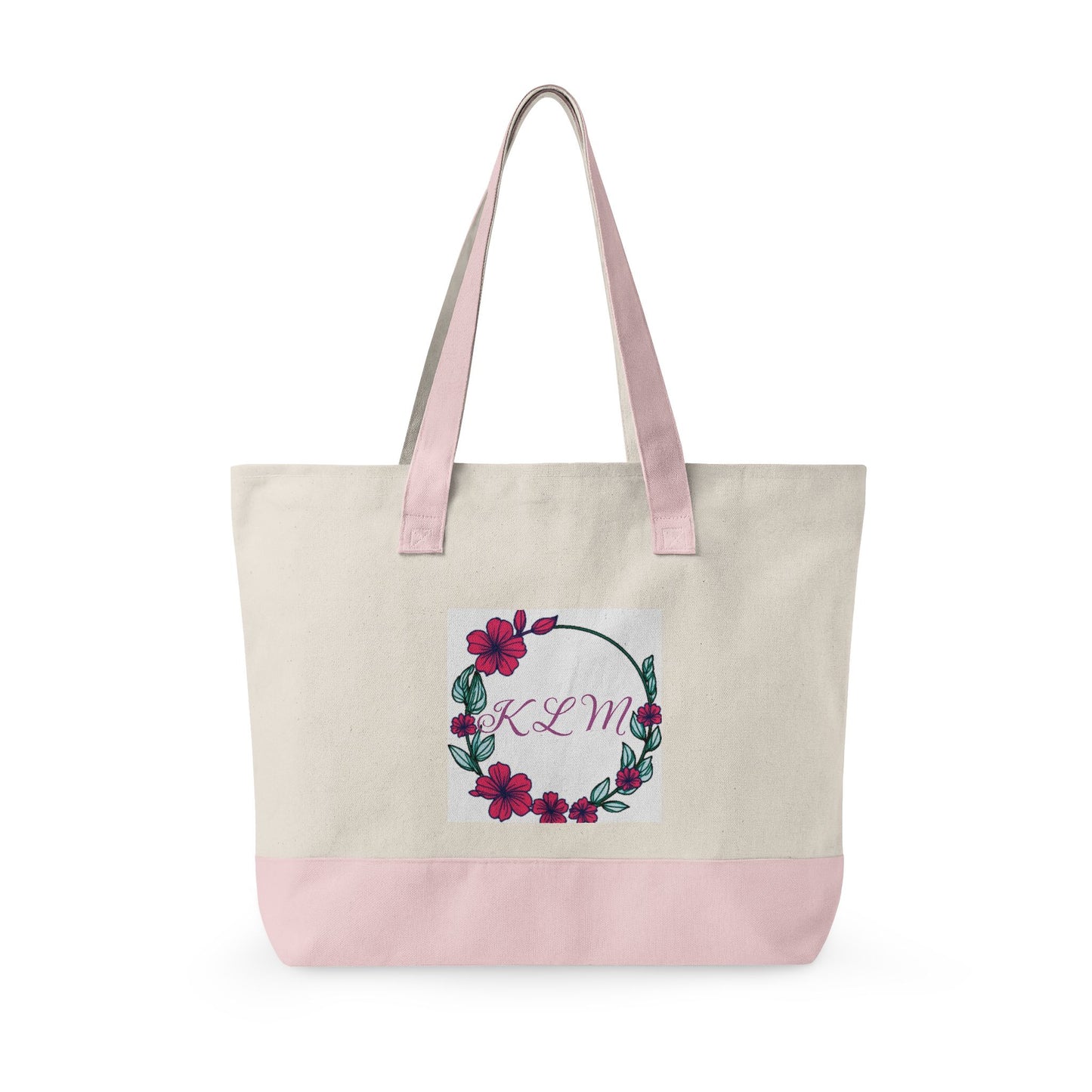 Cream fabric tote bag with pink handles and base, featuring a floral hibiscus wreath and the monogram KLM.