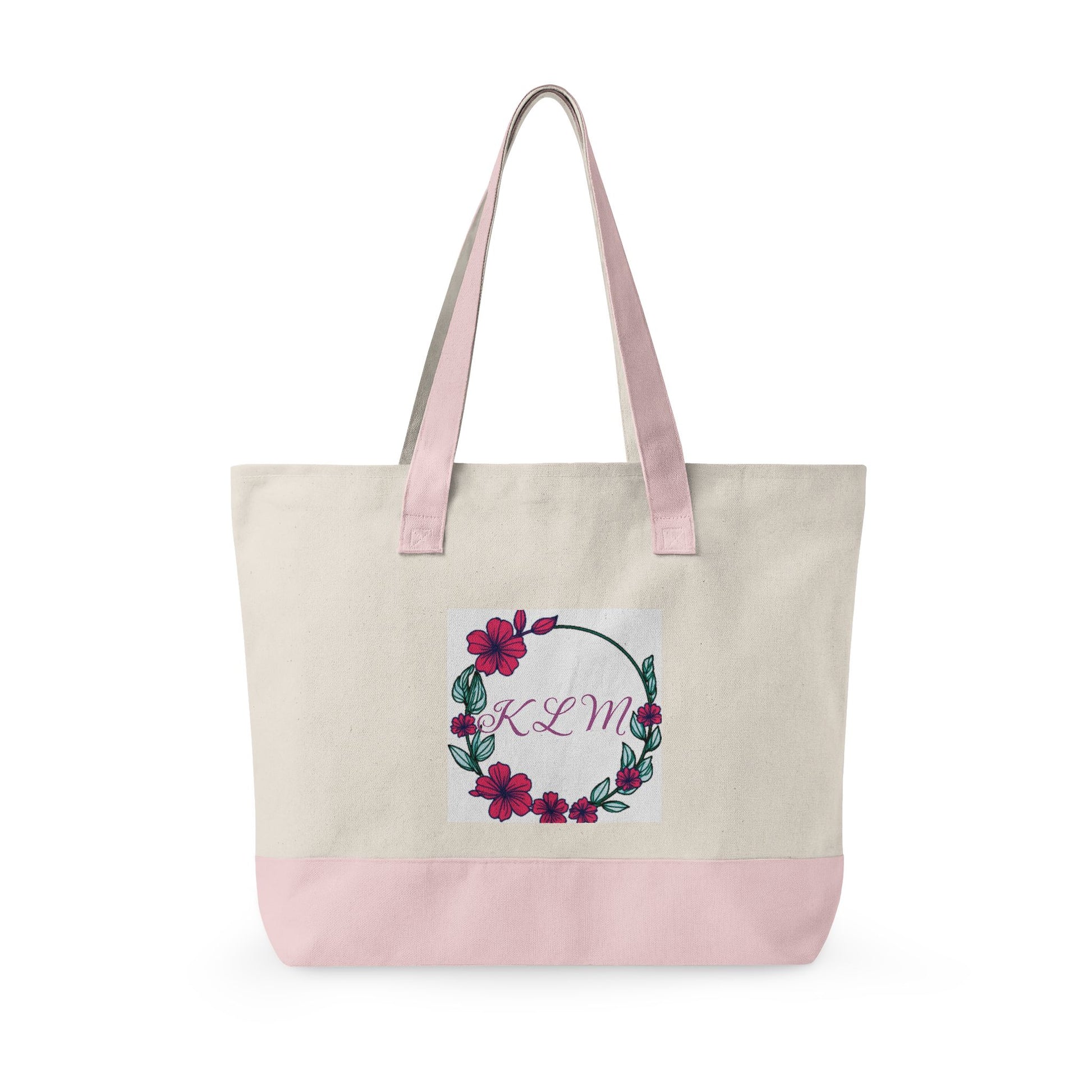 Cream fabric tote bag with pink handles and base, featuring a floral hibiscus wreath and the monogram KLM.