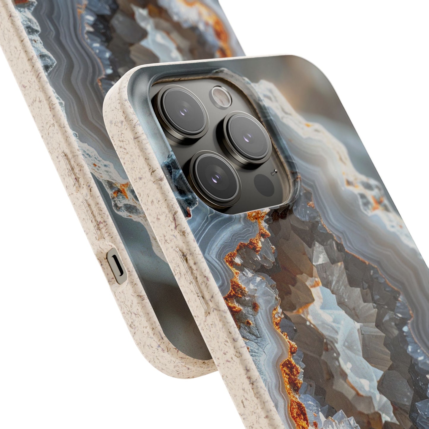 A close-up of a smartphone case with a geode-inspired agate pattern in gray, blue, white, and rust-orange tones, with a speckled beige bumper edge. The phone camera module is visible through a cutout in the back of the case.