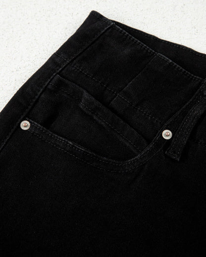 Close-up of black jeans with button details on a light gray background