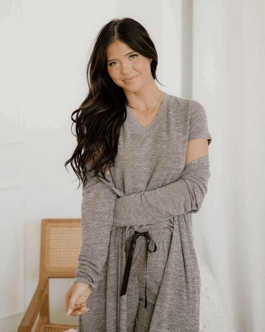 Woman wearing a gray robe in a minimalistic room.