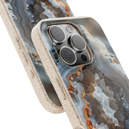 A close-up of a smartphone case with a geode or agate-inspired pattern in gray, blue, white, and rust-orange tones, with a thick textured beige bumper edge. The phone camera cutout is visible, and the case is shown against a plain white background.