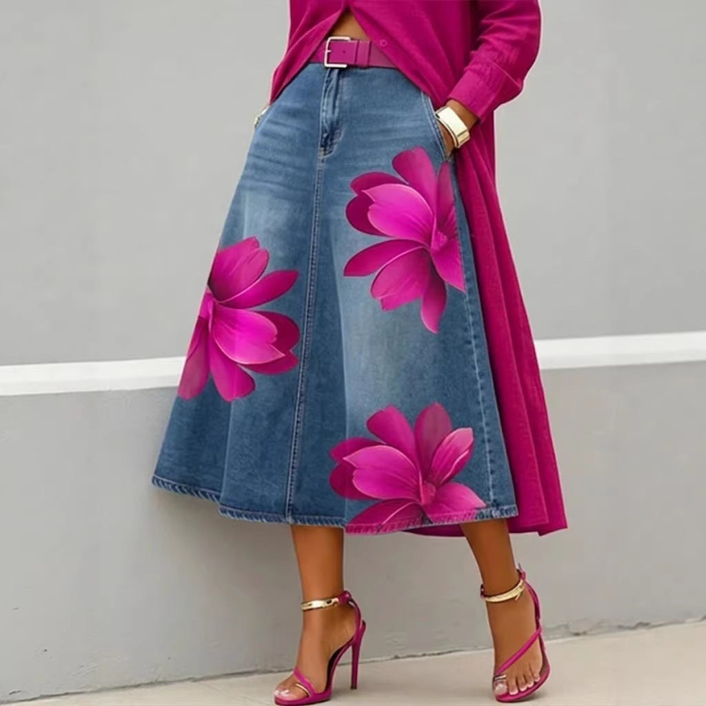 Person wearing a denim skirt with pink floral designs and a pink top against a gray background
