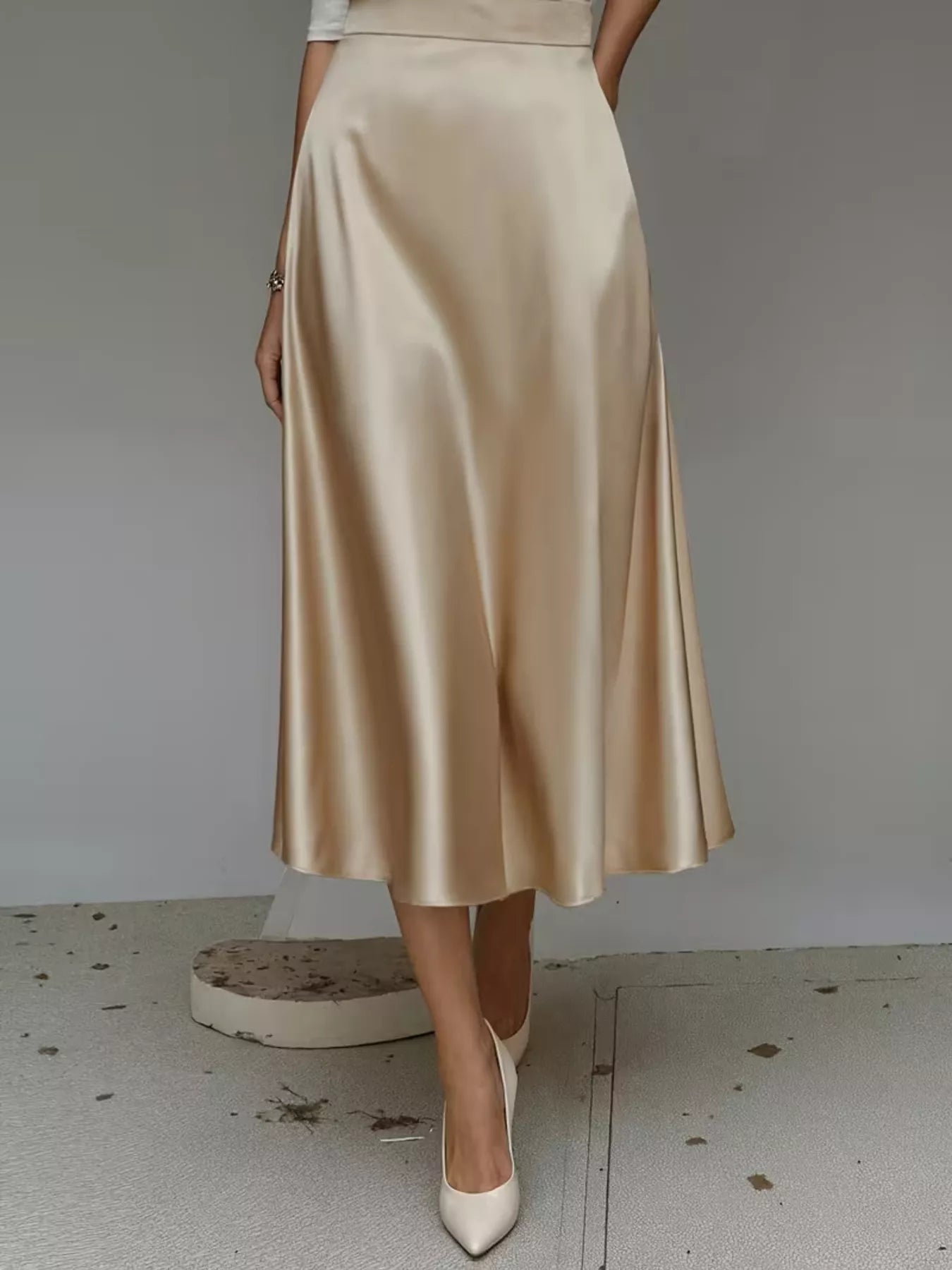 Beige satin skirt worn by a person on a plain background