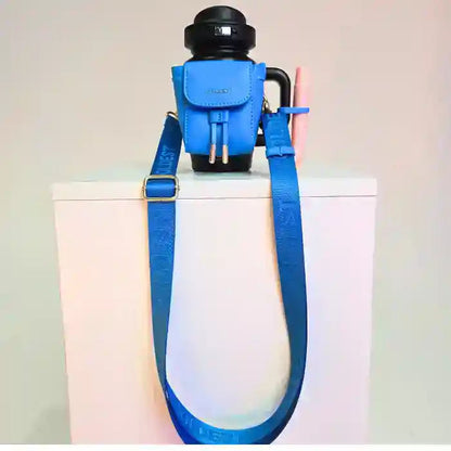 Coldest water bottle in black with a blue mini backpack holder and strap, placed on a white surface.