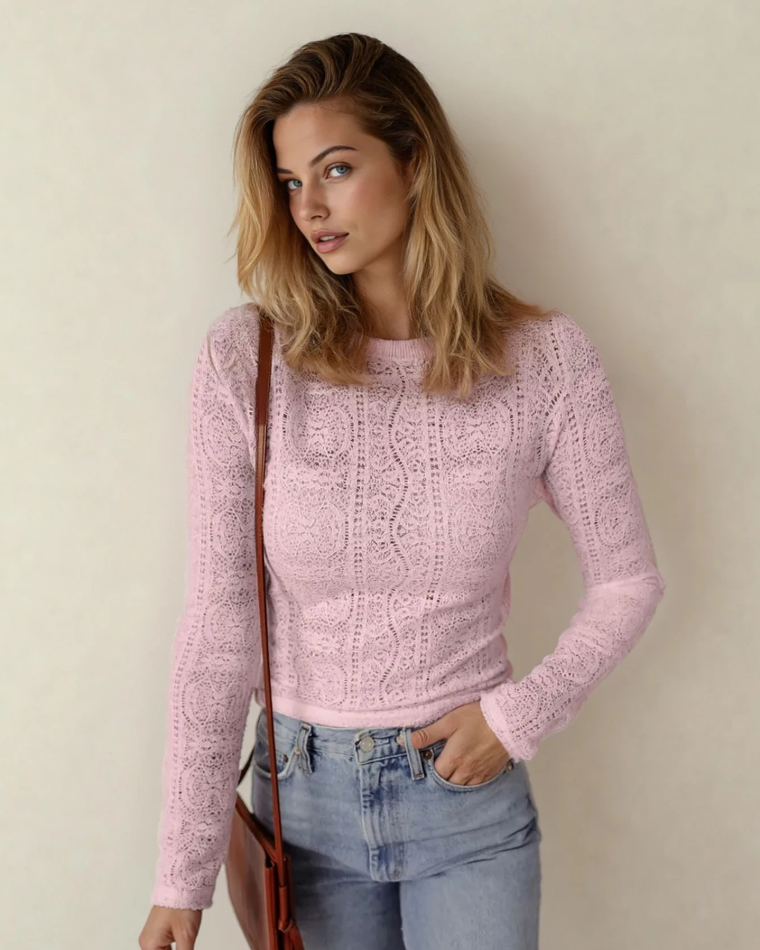 Woman wearing a pink knitted sweater and blue jeans against a plain background