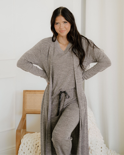 Woman wearing a gray loungewear set with a long cardigan in a minimalistic room.