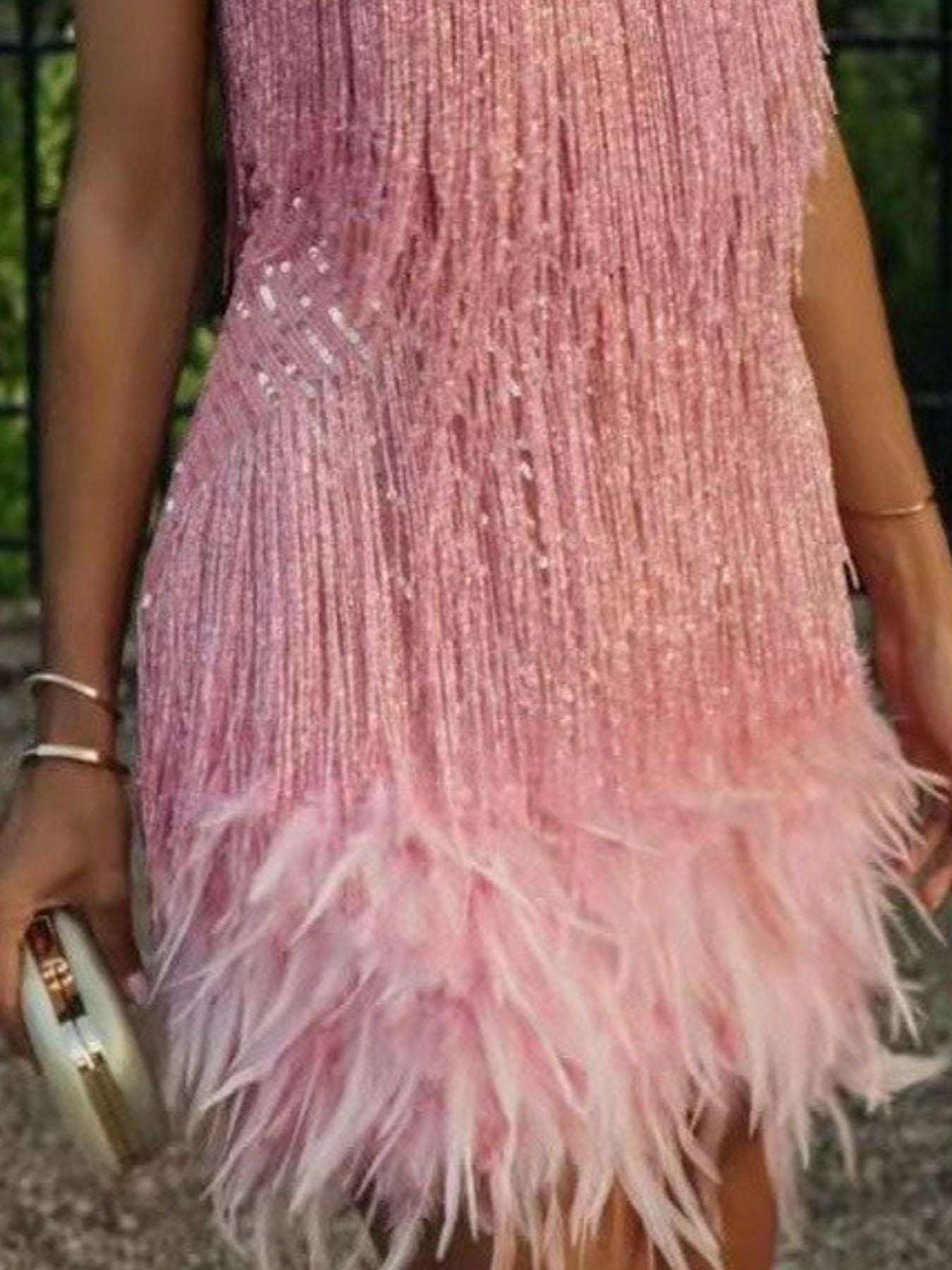Close-up of a pink dress with feather details and a blurred background