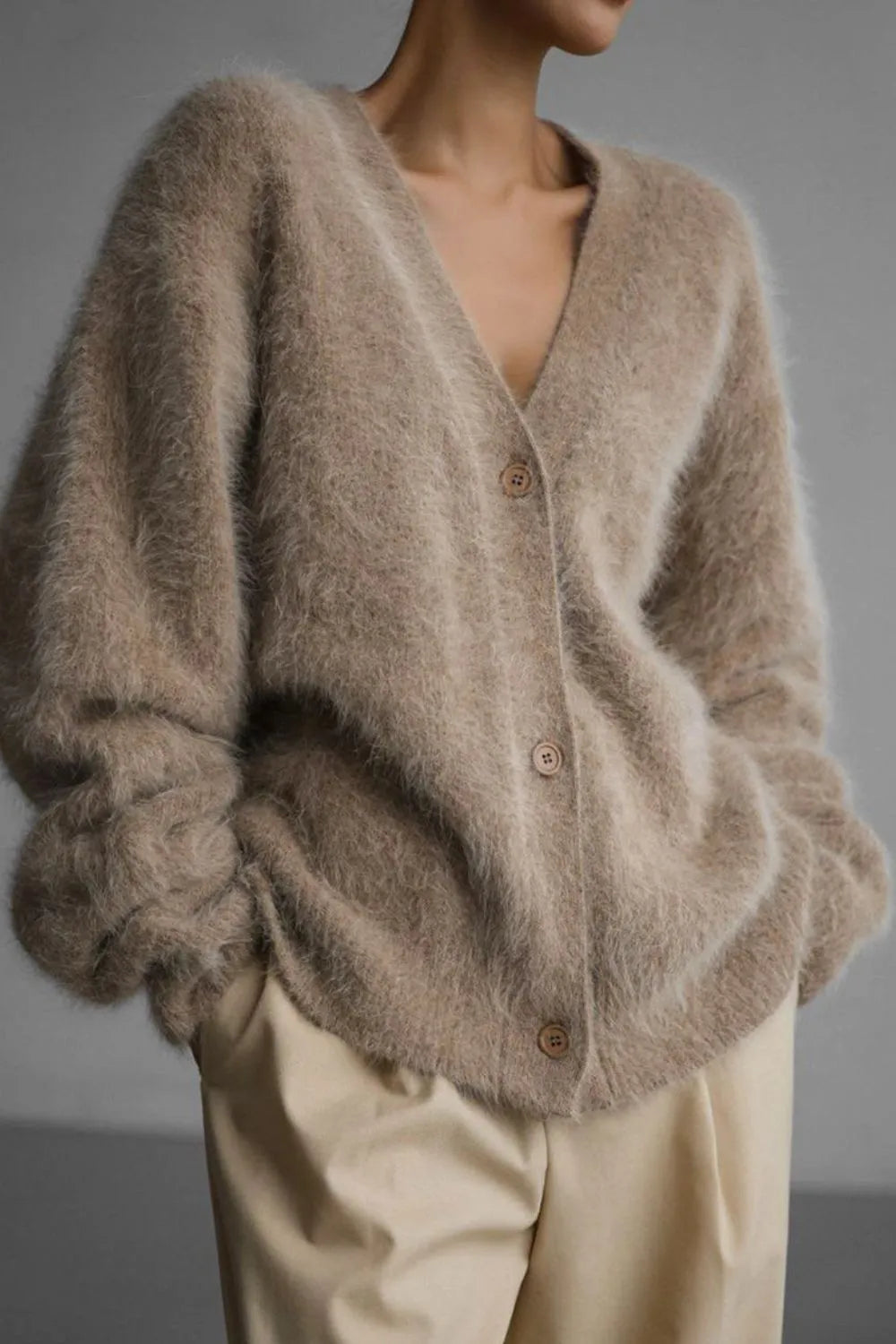 Beige cardigan worn by a person on a gray background