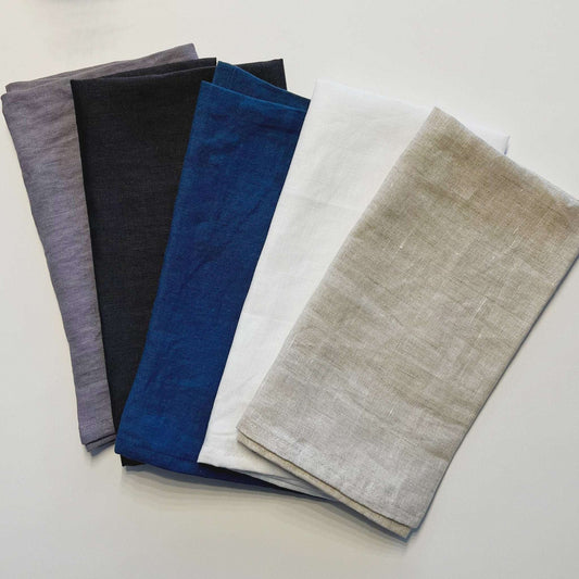 Five folded fabric swatches in gray, black, blue, white, and beige on a light gray background