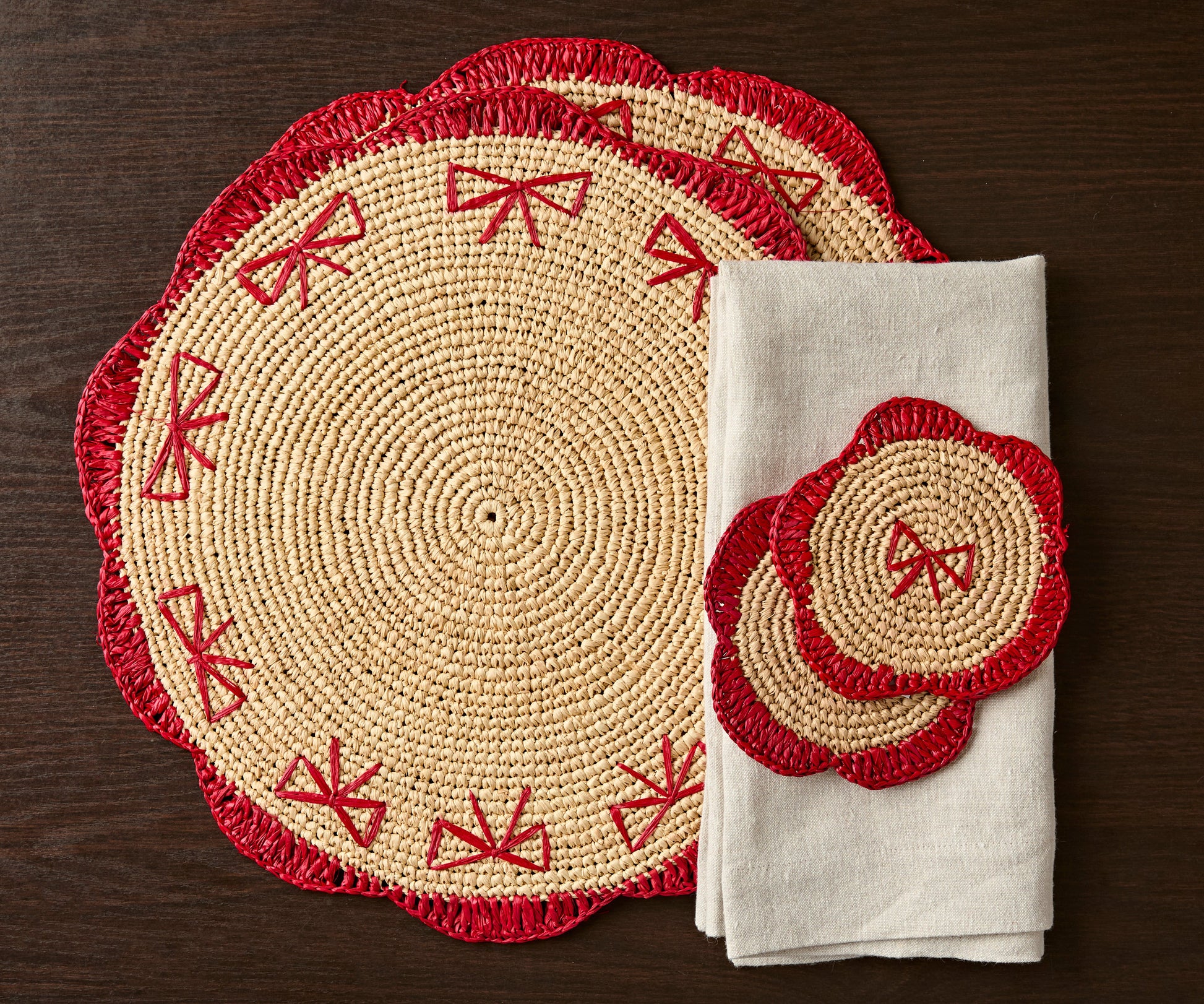 Handwoven raffia fringe coaster set with red accents, featuring a round design and accompanying beige napkin.