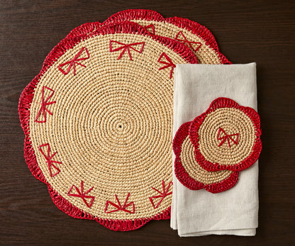 Handwoven raffia fringe coaster set with red accents, featuring a round design and accompanying beige napkin.
