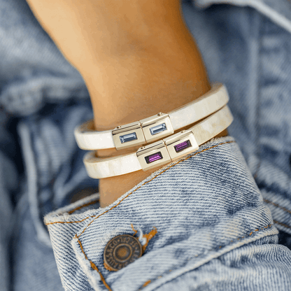 Close-up of a person wearing multiple bracelets with gemstone accents on a denim background