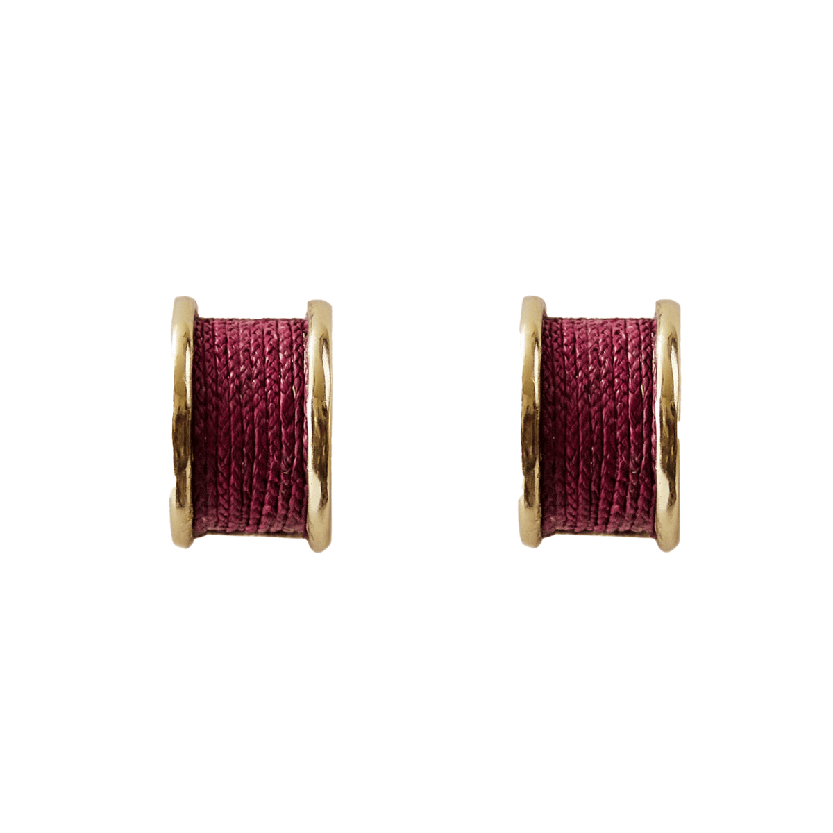 Pair of earrings with gold rims and red central components on a white background