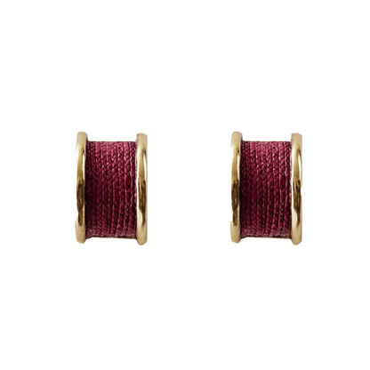 Pair of earrings with gold rims and red central components on a white background