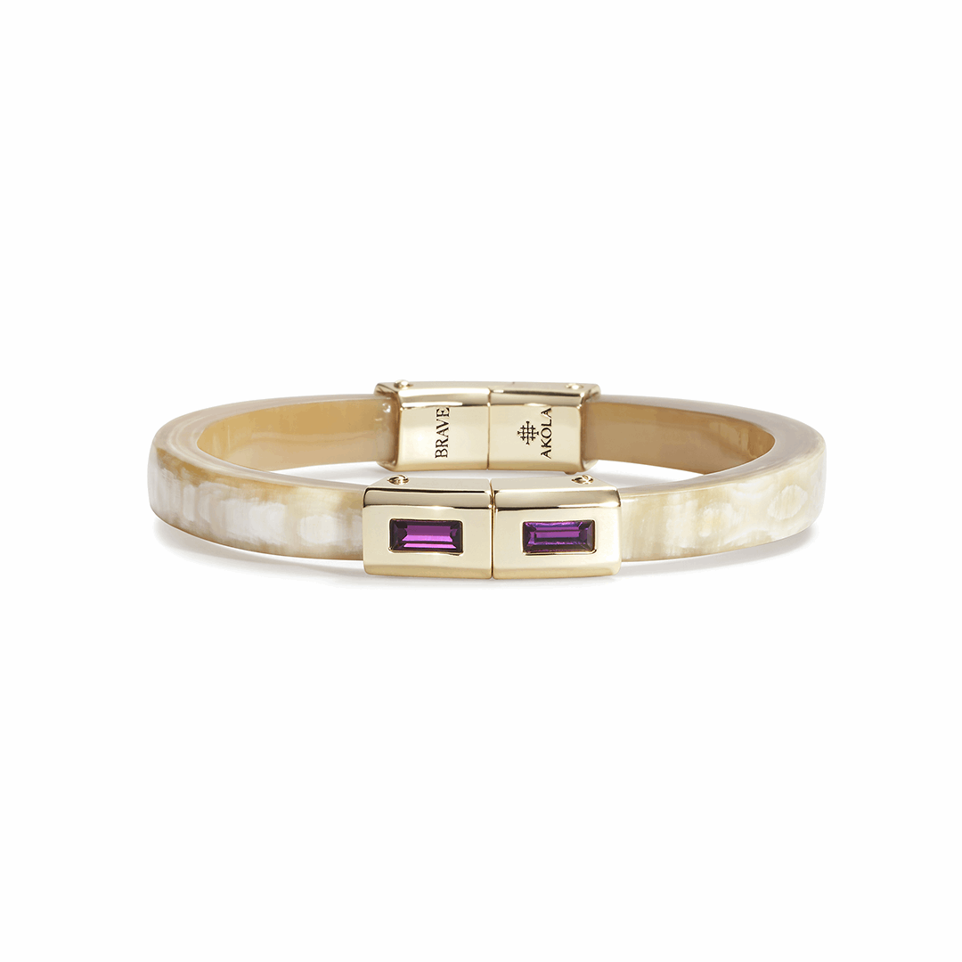 Gold bracelet with purple gemstones on a white background