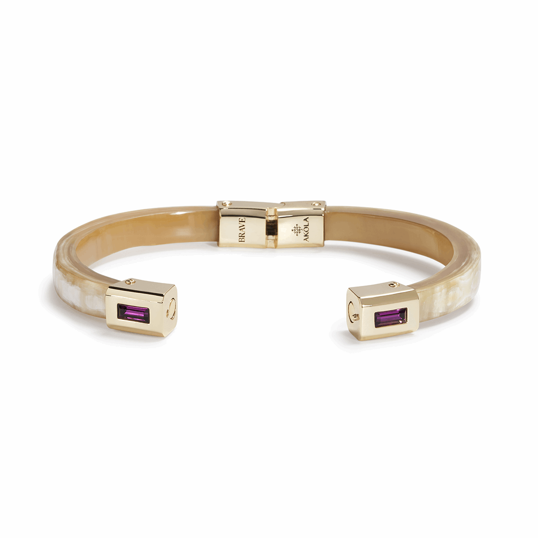 Gold bracelet with purple gemstones on a white background