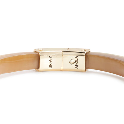 Beige bracelet with gold clasp on a white background