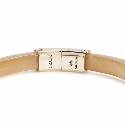 Gold bracelet with 'Grace' and 'Akola' branding on a white background