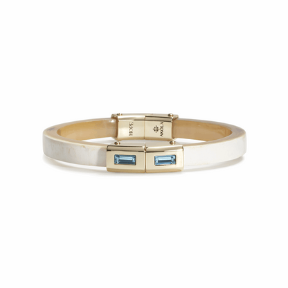 Gold bracelet with blue gemstones on a white background