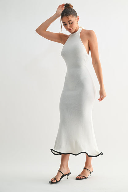 Woman wearing a white halter neck dress with black trim on a white background