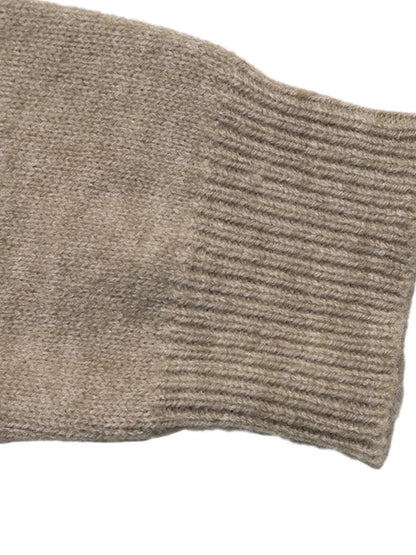 Close-up of a ribbed knit sleeve in a warm taupe-beige color on a white background.