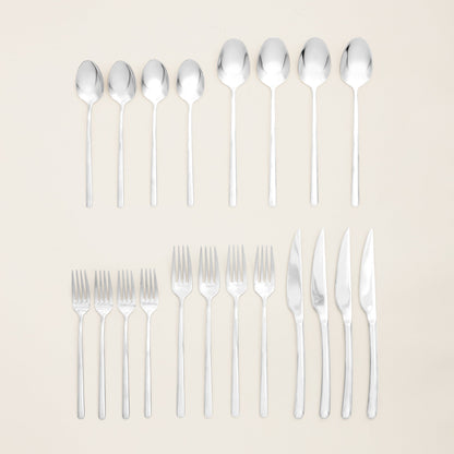 Set of silver cutlery including spoons, forks, and knives on a beige background