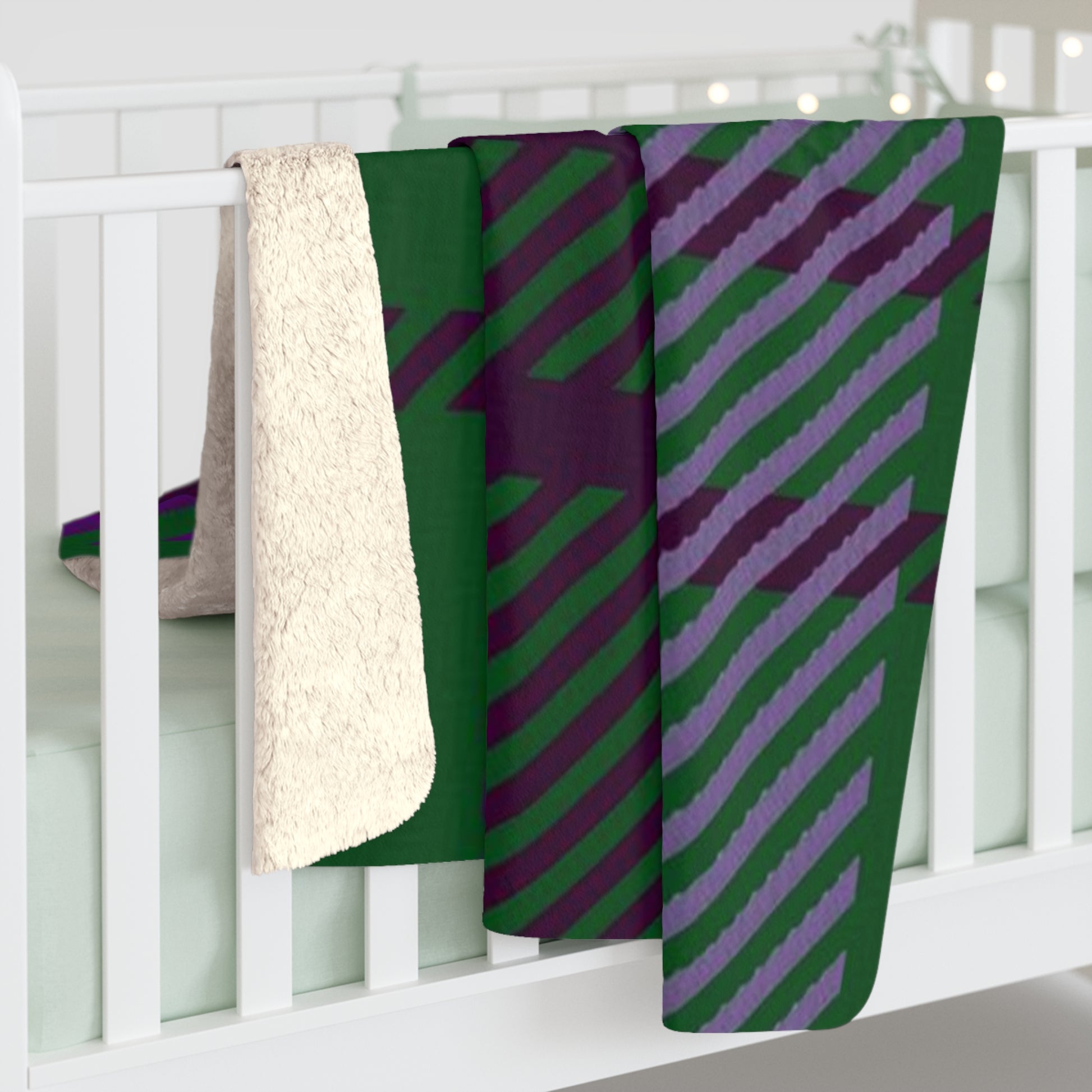 A folded baby blanket draped over a white crib, showing a green and purple diagonal striped pattern on one side and a soft cream sherpa fleece backing on the other.