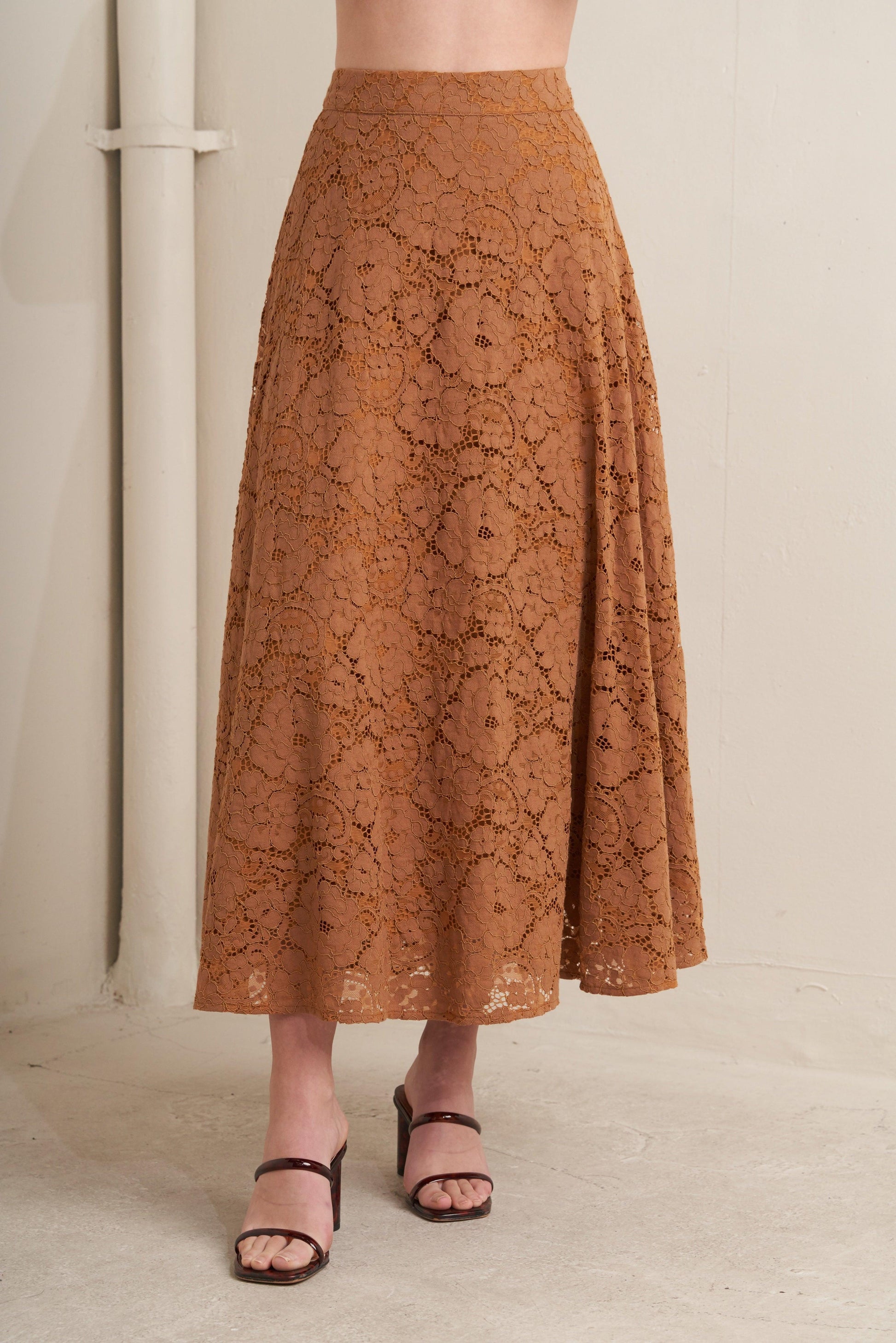Brown lace skirt worn by a person on a neutral background