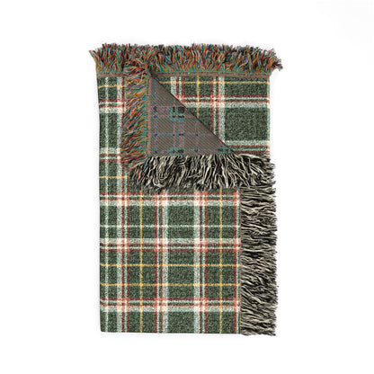 A folded plaid throw blanket with fringed edges, featuring a green, white, and red tartan pattern with a gray reverse side, shown on a plain white background.