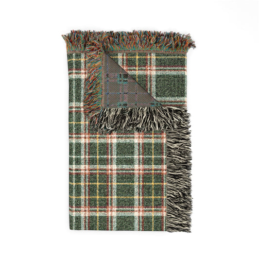 A folded plaid throw blanket with fringed edges, featuring a green, white, and red tartan pattern with a gray reverse side, shown on a plain white background.