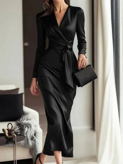 Person wearing a black satin dress in a room with a couch and window.