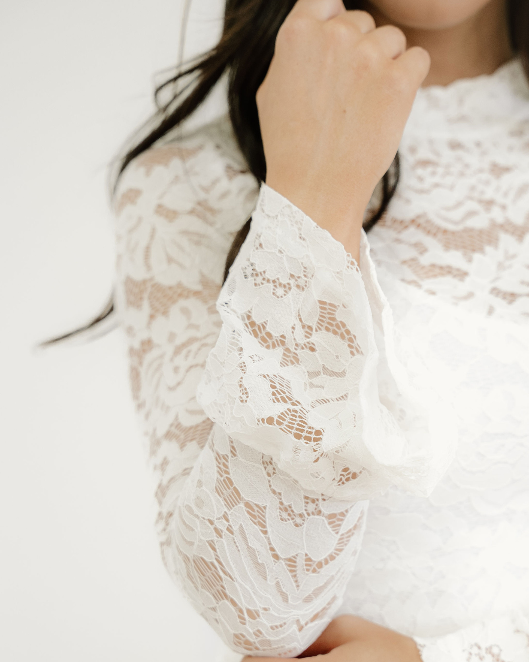 Close-up of a person wearing a white lace dress with a blurred background
