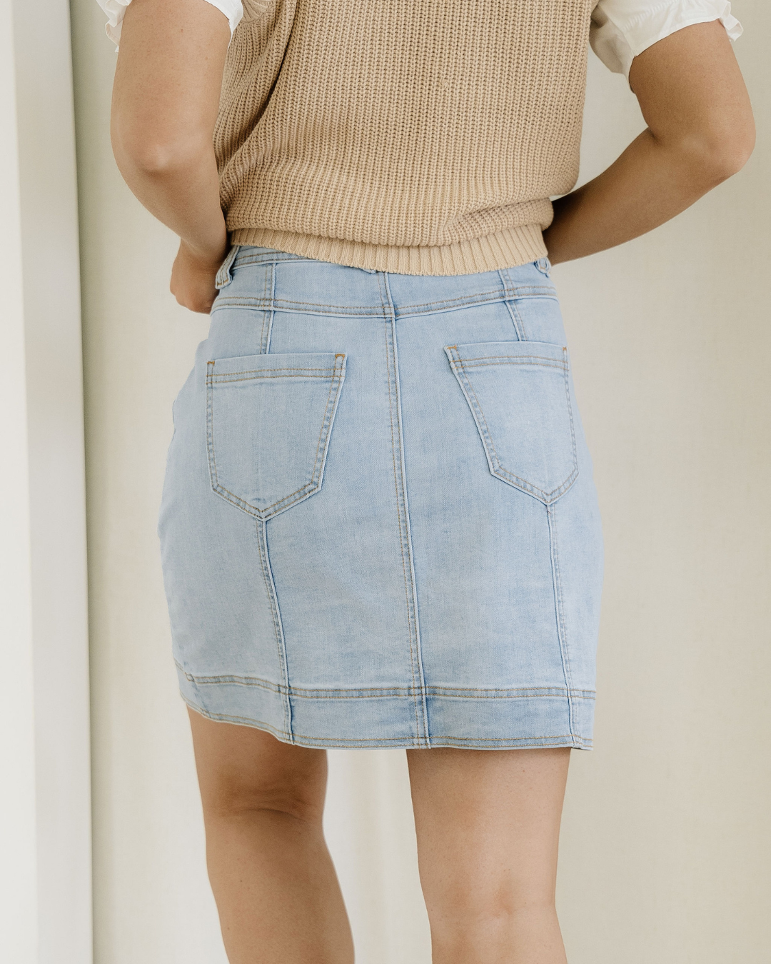 Light blue denim skirt worn by a person on a plain background