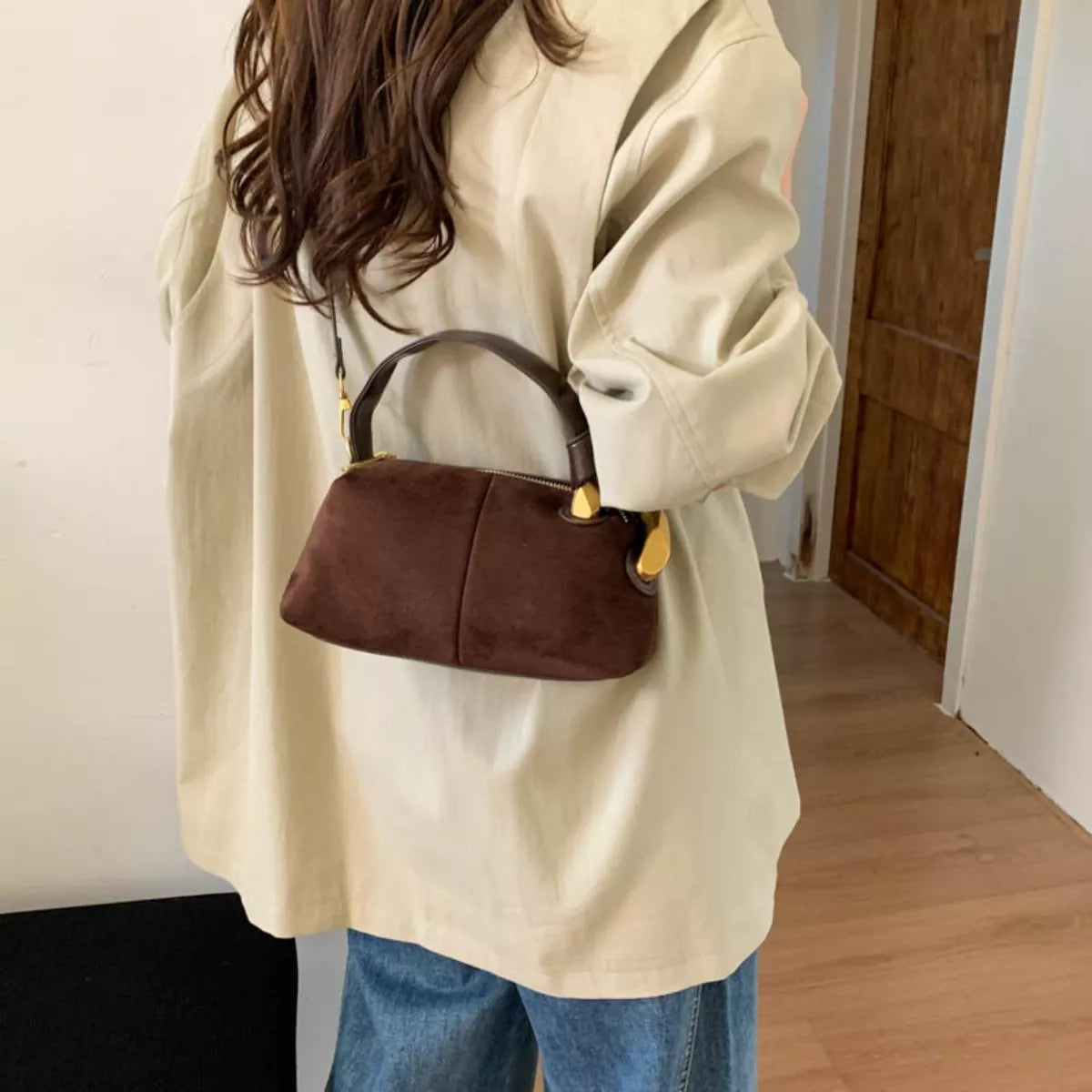 Person holding a brown handbag indoors