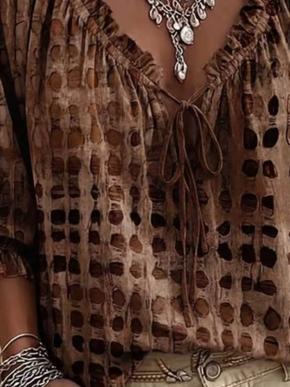 Close-up of a brown bohemian-style top with a distressed, perforated pattern, featuring a ruffled V-neckline with a tie closure and a tie-dye effect.
