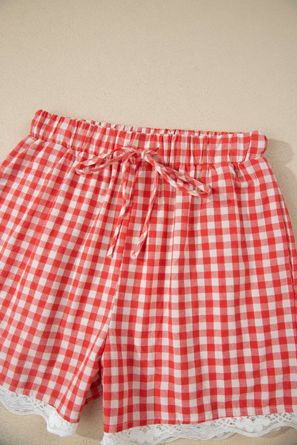 Red and white gingham fabric shorts with an elastic drawstring waist and white lace trim at the hem.