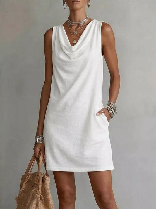 Woman wearing a white sleeveless dress against a plain background