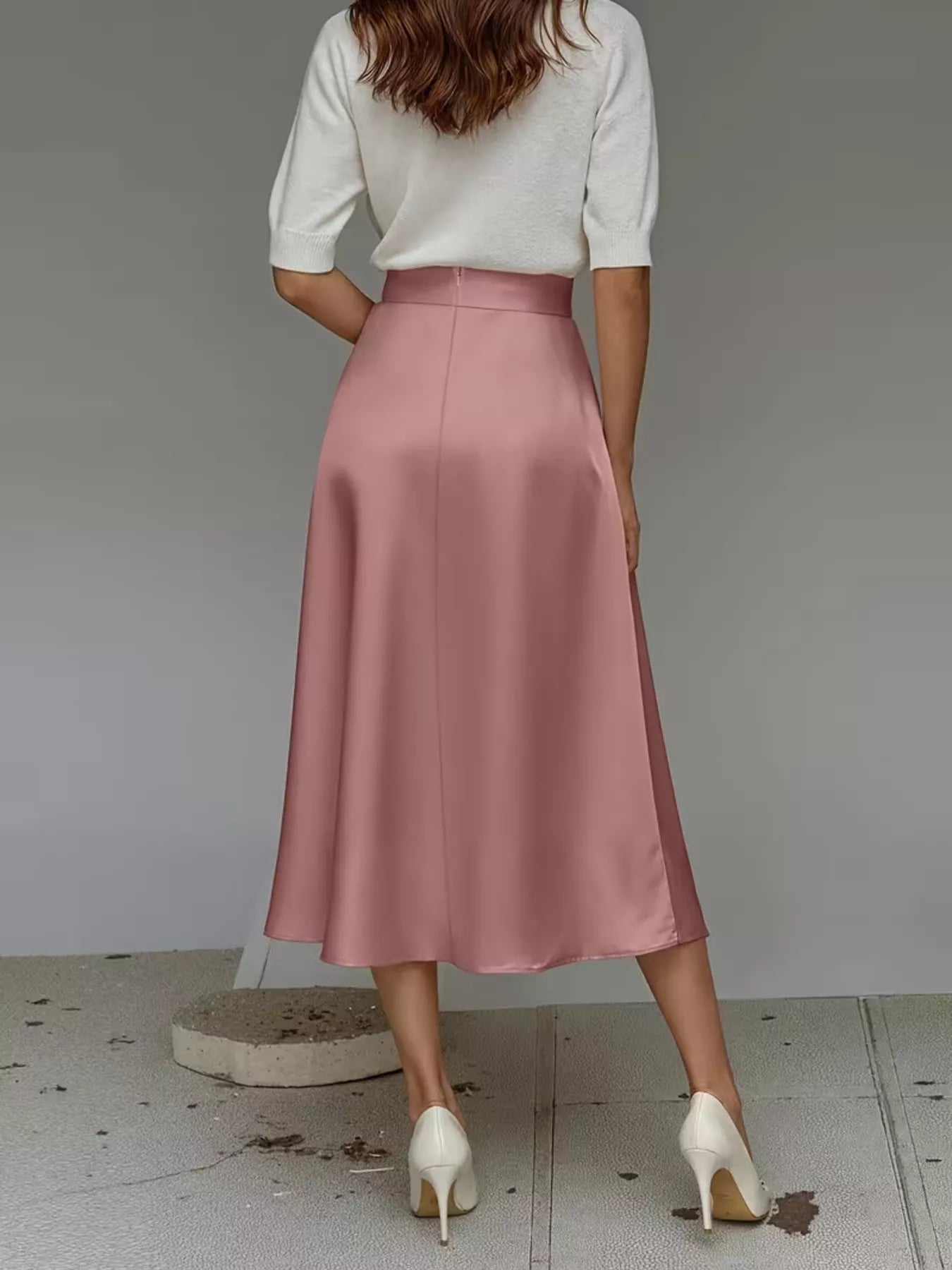 Person wearing a white top and pink satin skirt on a plain background