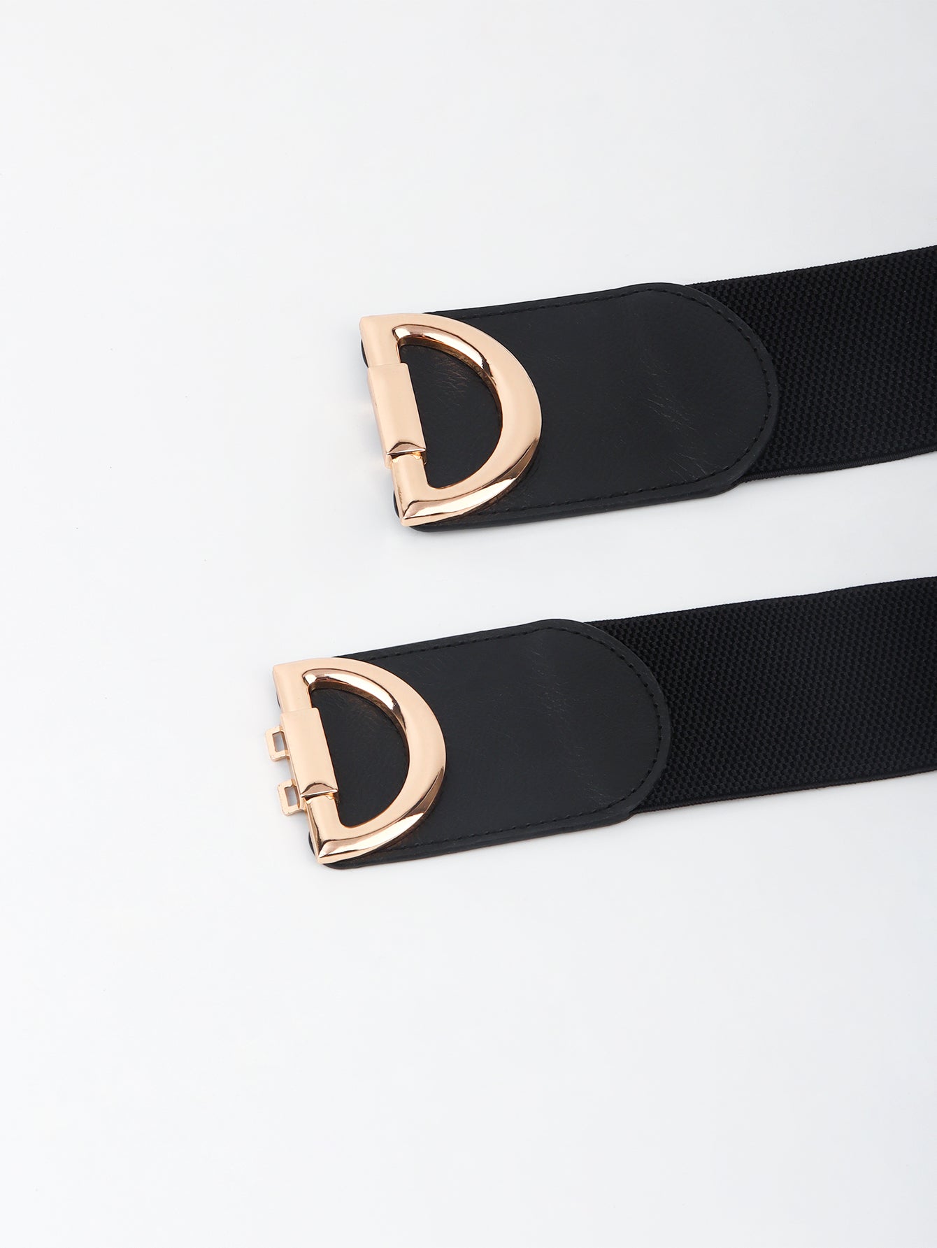 Black belt with rose gold D-ring buckle on a light gray background