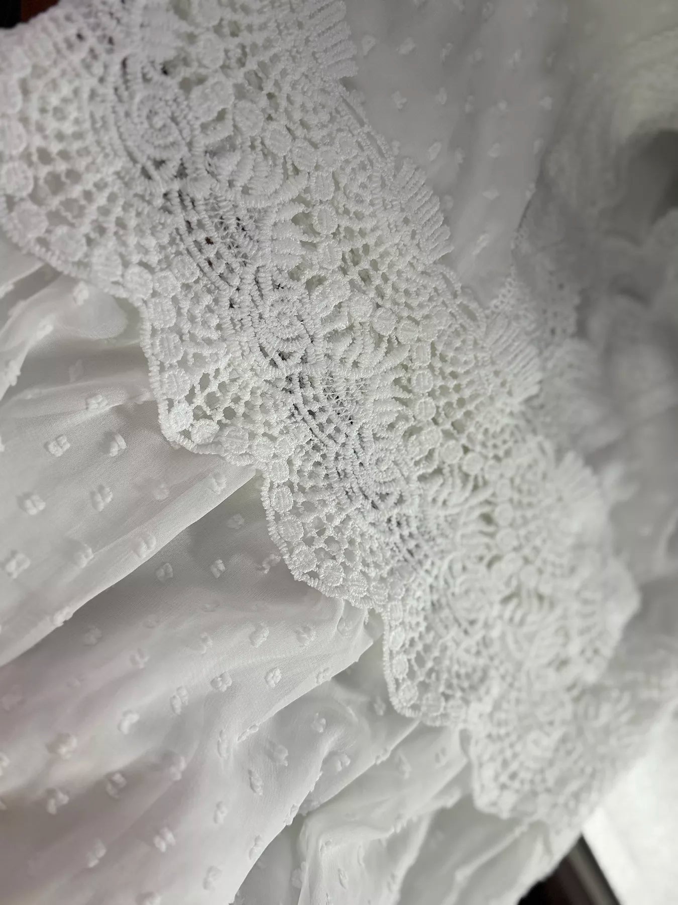 Close-up of a white lace trim on a textured fabric background