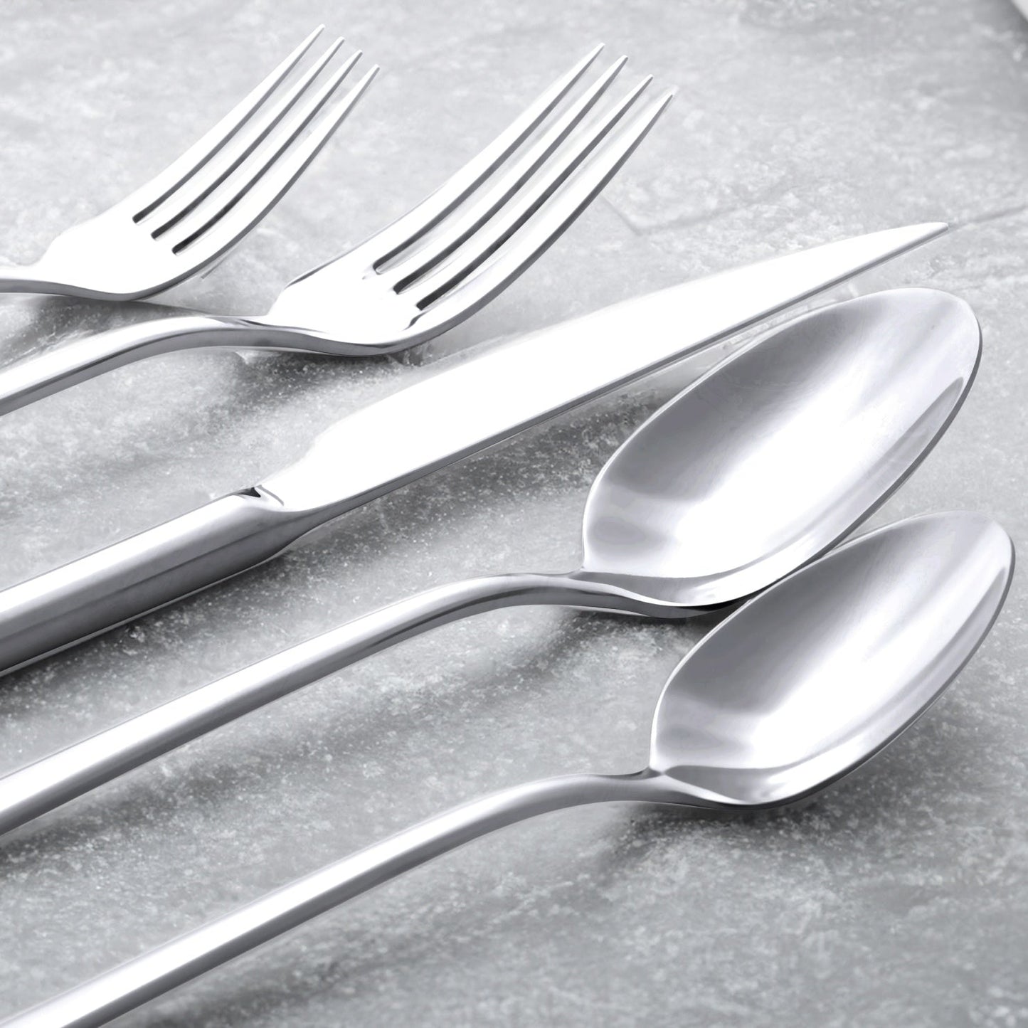 Set of silver forks and spoons on a gray surface