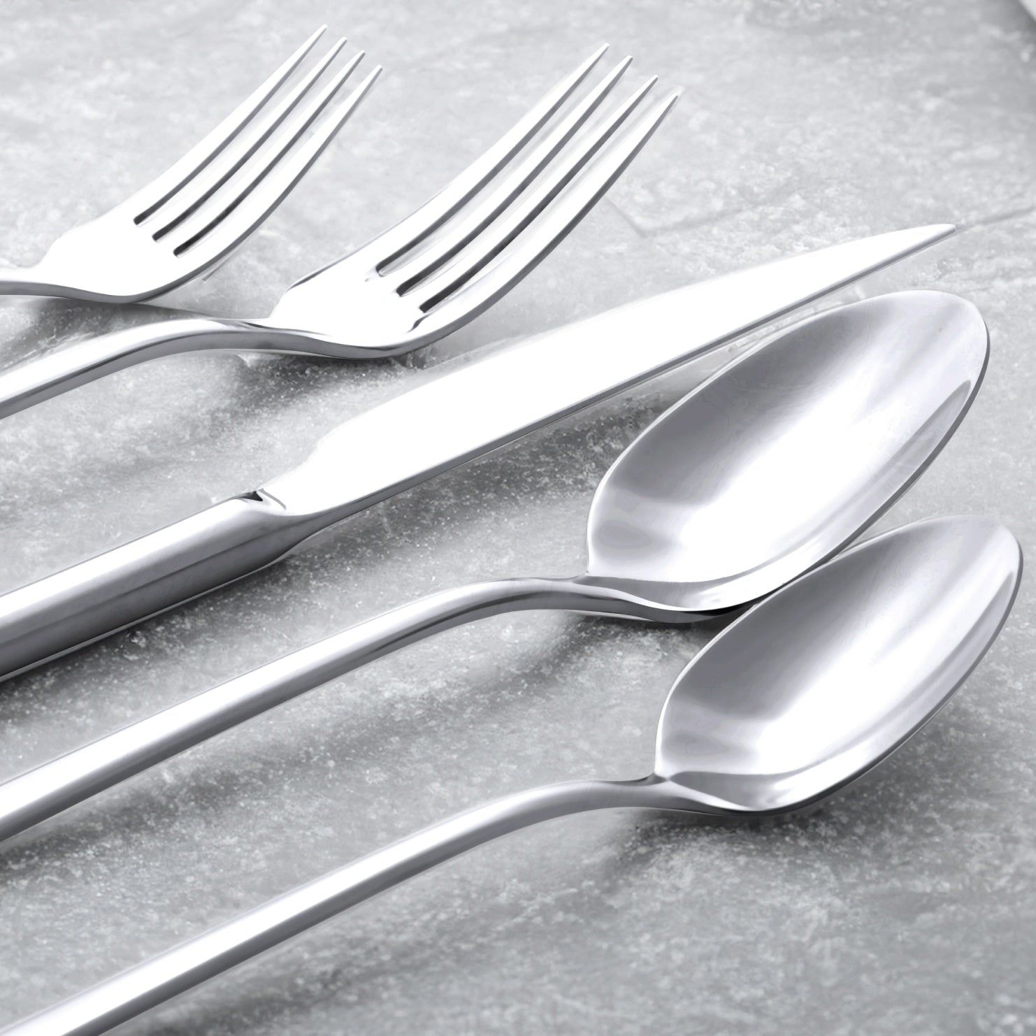 Set of silver forks and spoons on a gray surface