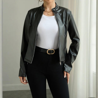 Person wearing a black leather jacket over a white top and black pants, standing against a neutral background.