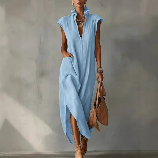 Woman wearing a light blue dress holding a brown handbag against a plain background