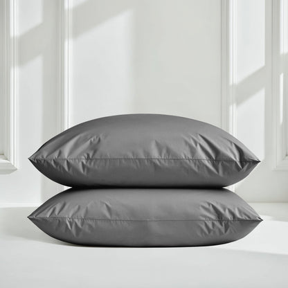 Two gray pillows on a white surface with a neutral background