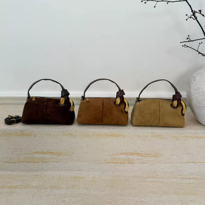 Three suede handbags in brown, tan, and beige on a light wooden floor.