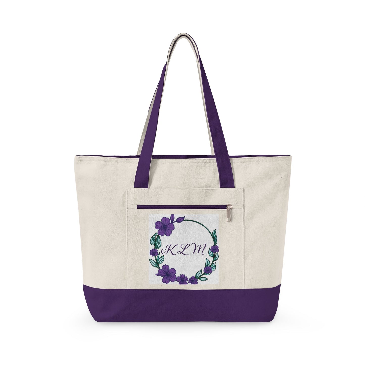 An off-white canvas tote bag with a solid purple bottom panel and matching purple shoulder straps. The front features a zippered pocket decorated with a purple floral wreath and the monogram 'KCM'.