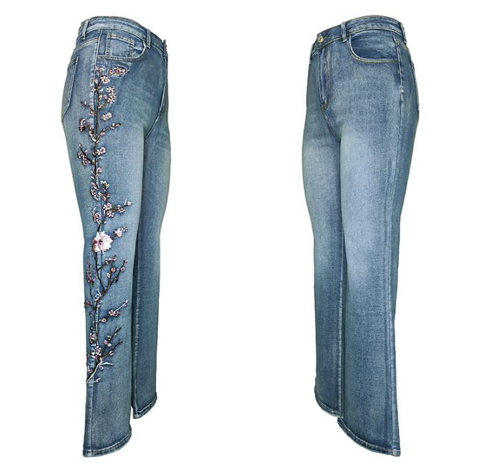 A pair of light blue denim jeans shown from the front and back. The back view features a vertical floral embroidery design in pink, purple, and black thread running down the left leg.